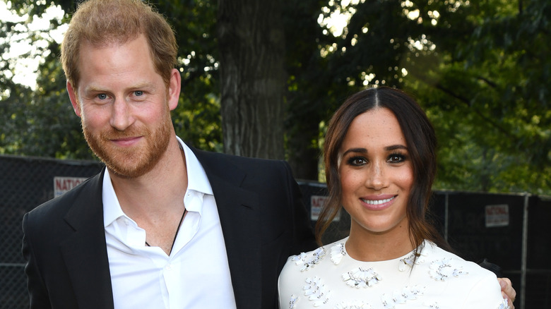 Prince Harry and Meghan Markle posing outside surrounded by trees