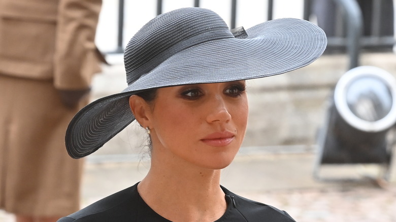 Closeup of Meghan Markle in wide-brim black hat at the queen's funeral