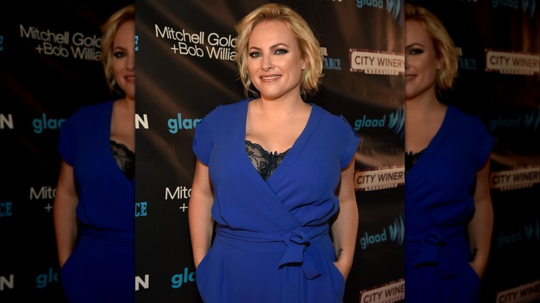 Meghan McCain on the red carpet in a blue jumpsuit with her lacy black bra on display