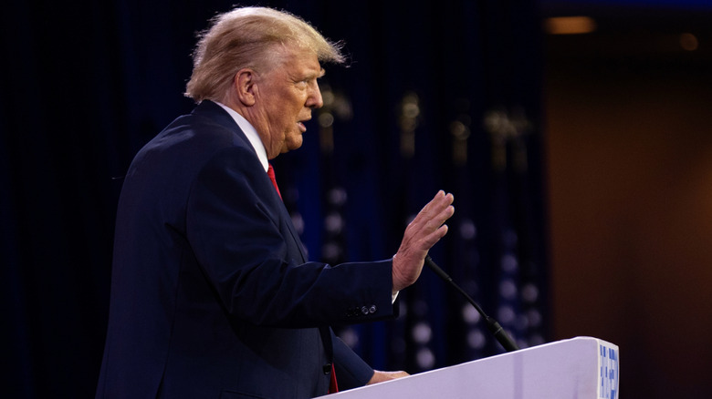 Trump with hand up giving speech at podium