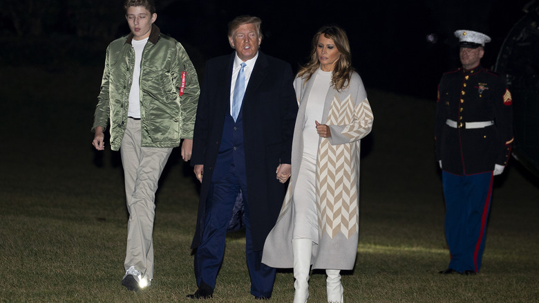 Barron, Donald, and Melania Trump walking across lawn