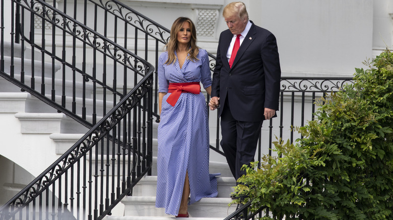 Melania and Donald Trump holding hands walking down steps outside