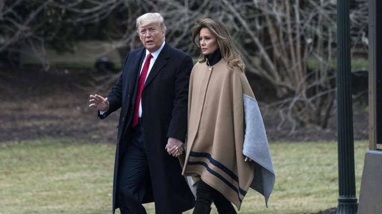 Melania and Donald Trump holding hands walking outdoors