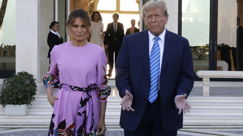 Donald Trump hands open Melania Trump purple jumpsuit