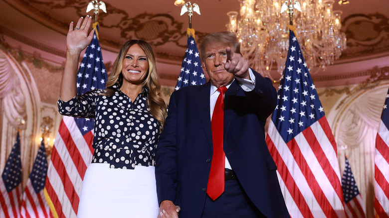 Melania Trump waving while Donald Trump points