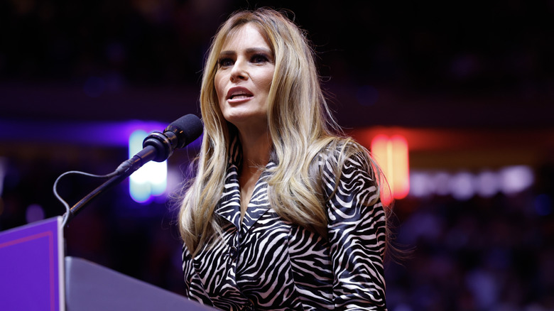 Melania Trump speaking at podium micrphone, zebra-print blouse