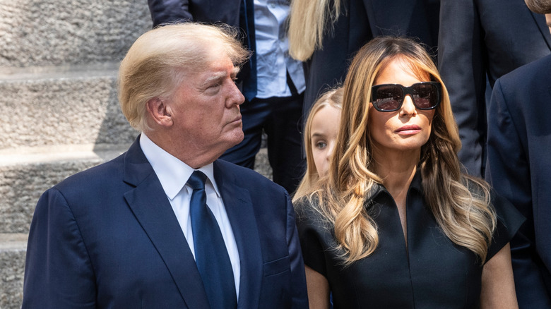 Donald Trump standing next to Melania in sunglasses