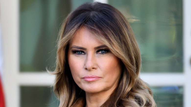 Melania Trump standing in front of an American flag