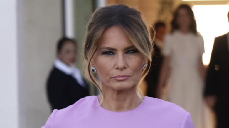 Melania Trump purple top updo serious expression