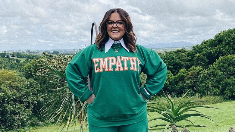 Melissa McCarthy in front of a lush green background 