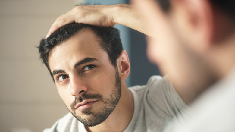 guy inspecting his face in a mirror