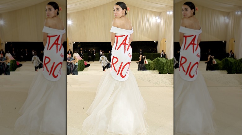 AOC in a white gown with Tax The Rich written in red