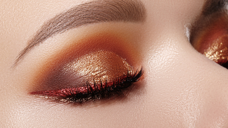 Woman with metallic gold eyeshadow and metallic cranberry winged eyeliner