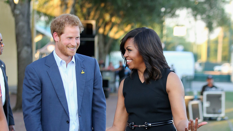 Prince Harry and Michelle Obama posing together and smiling