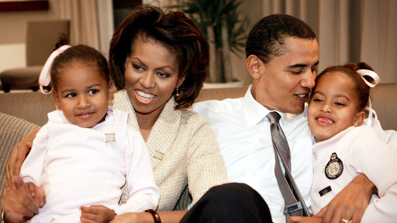 Michelle and Barack Obama holding young Sasha and Malia