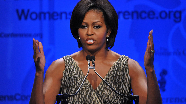 Michelle Obama talking and raising up her bare arms