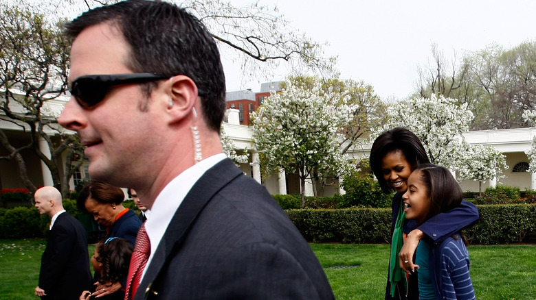 Secret Service agent walking in front of Michelle and Malia Obama