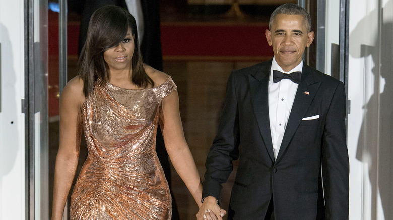 Michelle Obama holding hands with Barack Obama