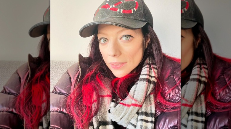 Michelle Trachtenberg wears a baseball cap and scarf.