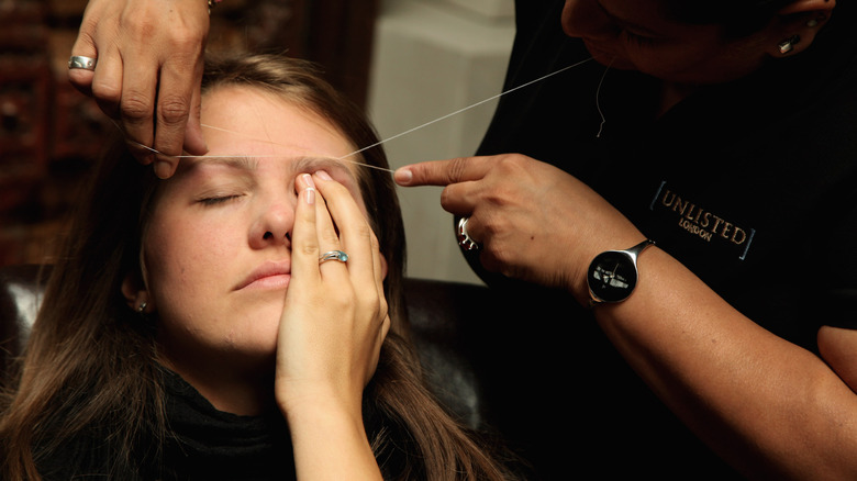 eyebrow threading a client's brow