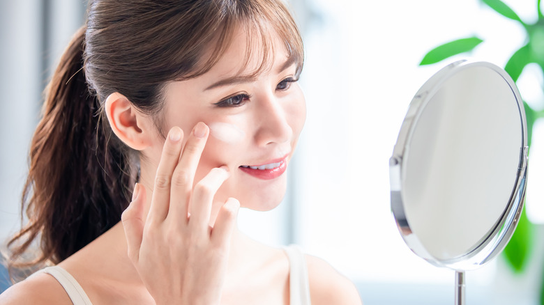 woman applying sunscreen in mirror