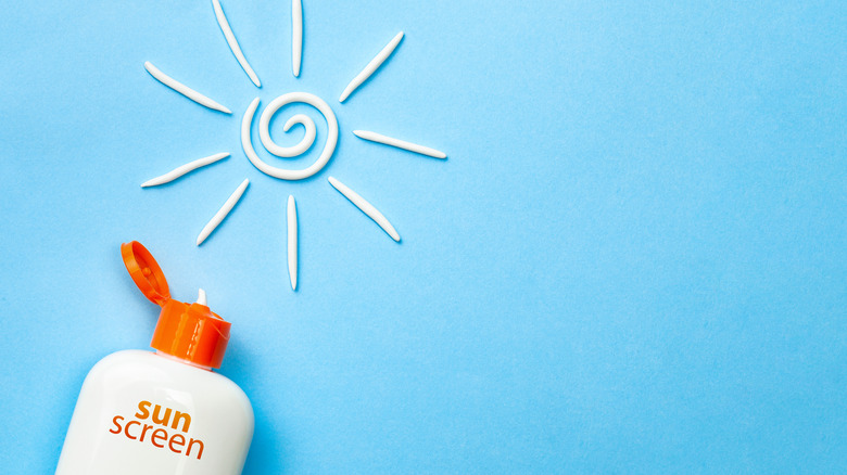 bottle of sunscreen and sun design using sunscreen on blue background