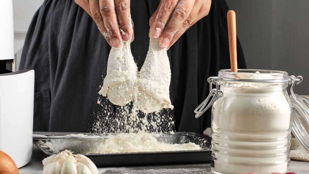 Person coating chicken in flour