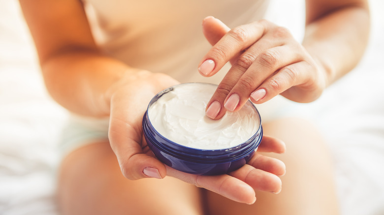 Woman dipping finger in moisturizer