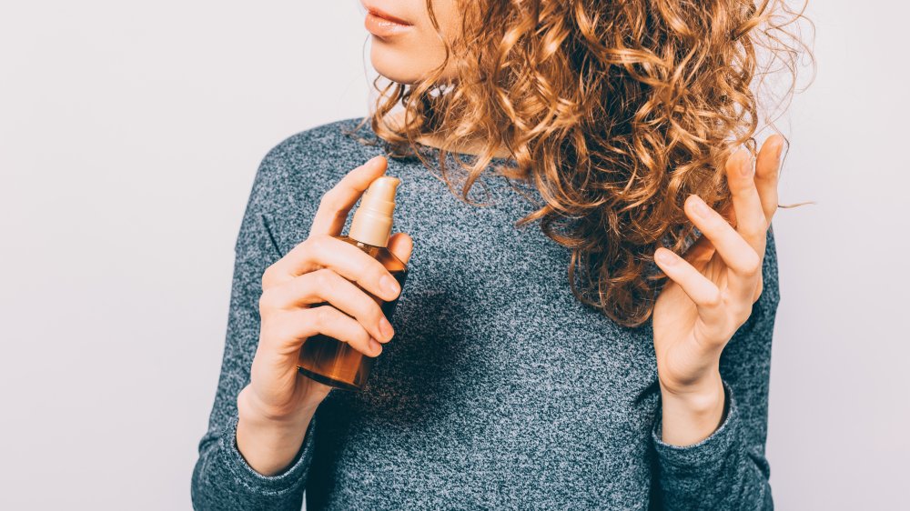 Woman spraying product into her hair 