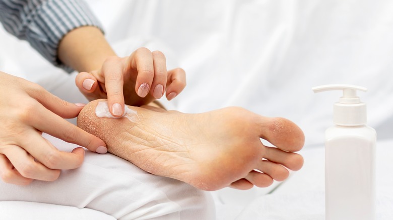 Woman putting lotion on heels