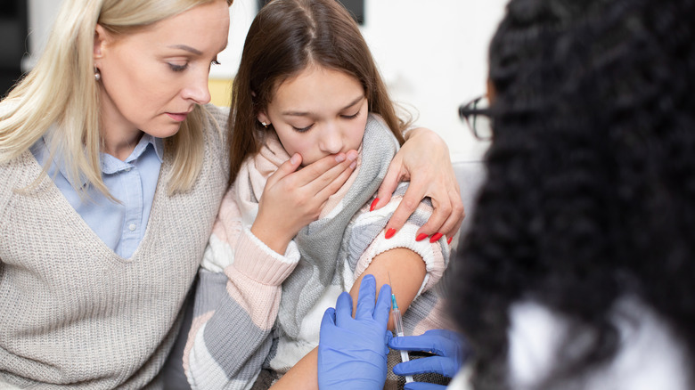 mom comforts teen getting vaccine