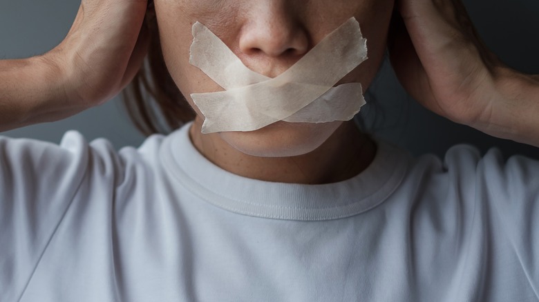 Woman with tape over mouth 