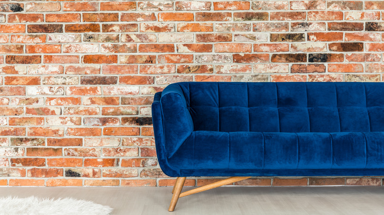 Cobalt blue couch against red brick background