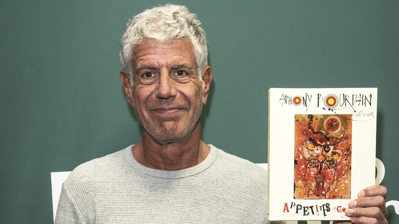 Anthony Bourdain holding one of his books