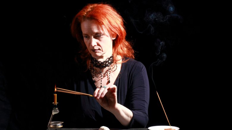 A redheaded woman lighting incense