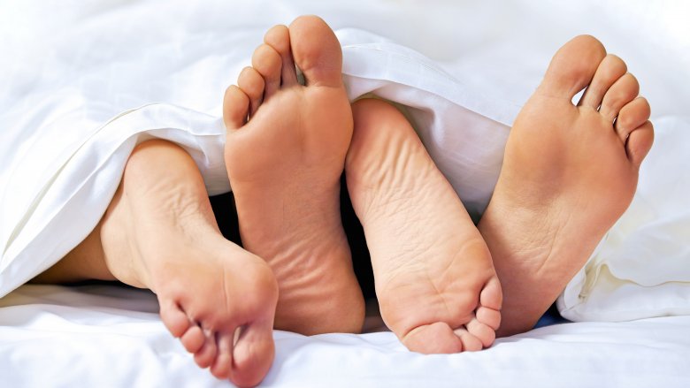 Two pairs of feet in bed