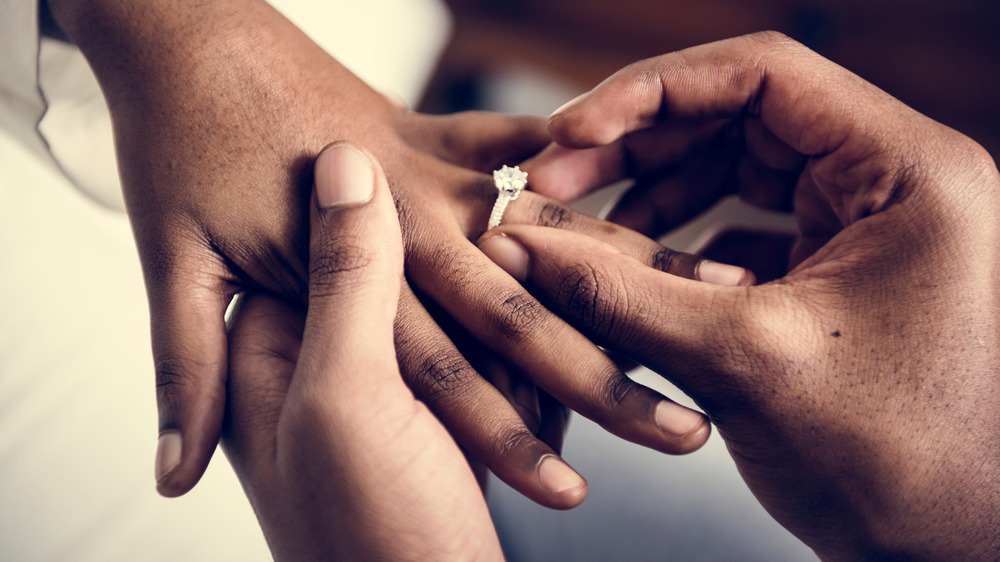 A groom slipping a ring onto the bride's hand, close-up