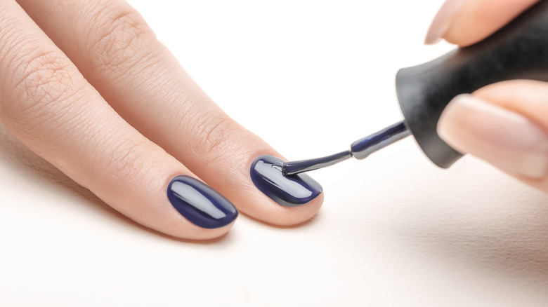 Person applying navy polish to nails