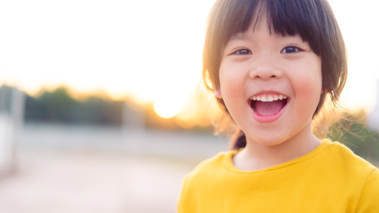 child smiling in a yellow shirt