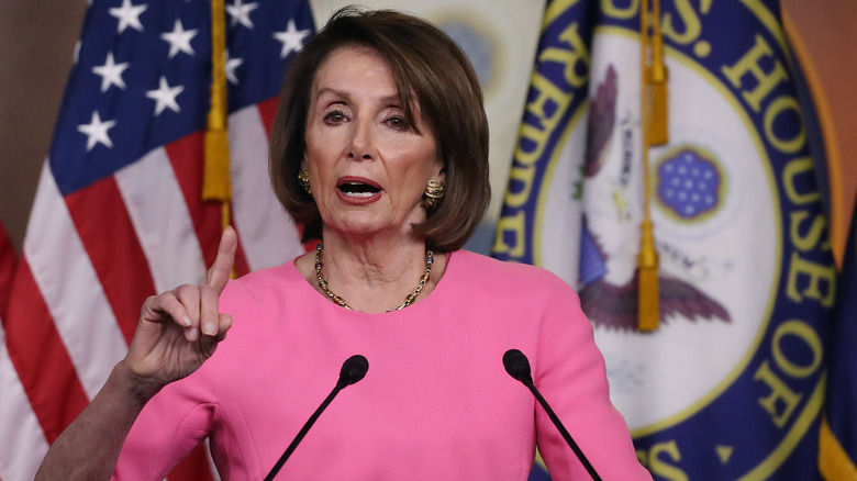 Nancy Pelosi in pink dress speaks at podium