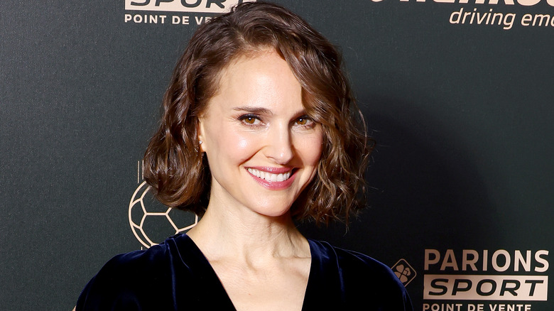 Natalie Portman grinning in a dark velvet dress