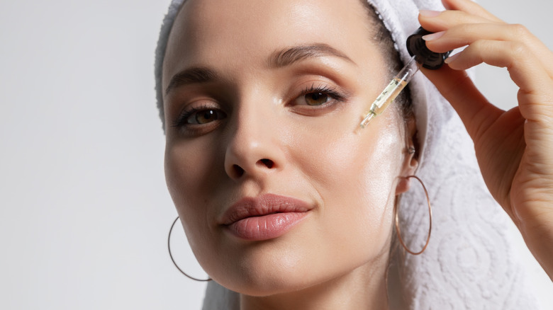 Woman applying facial oil to skin