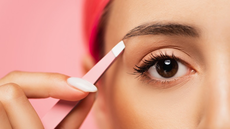 woman tweezing her eyebrows