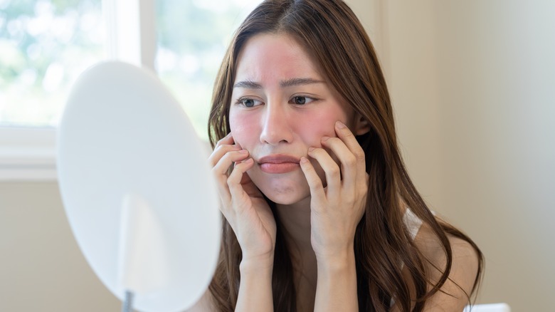 Woman looking at face in mirror