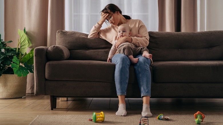 Tired mother holds baby on the couch