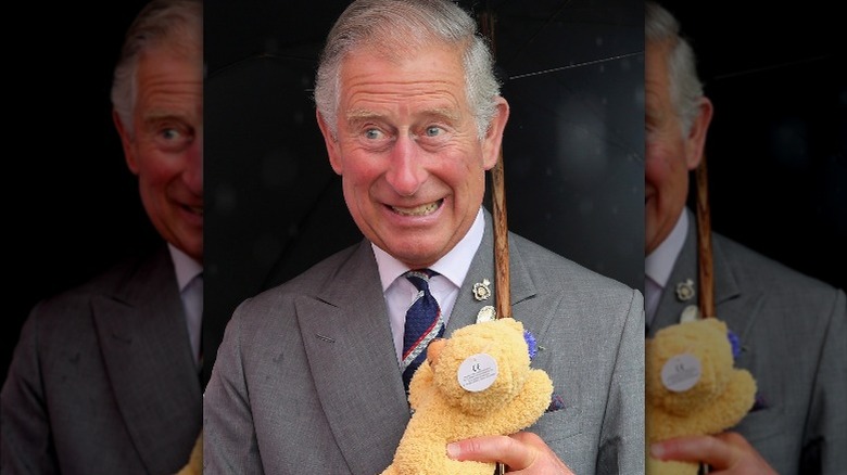 King Charles grinning while holding teddy bear