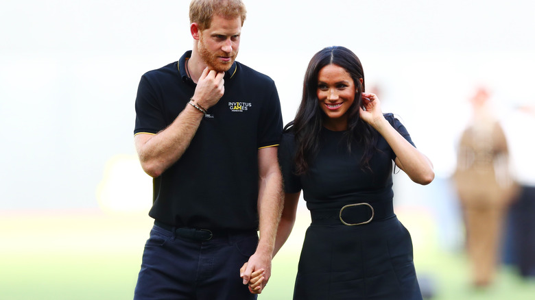 Prince Harry and Meghan Markle holding hands as they walk