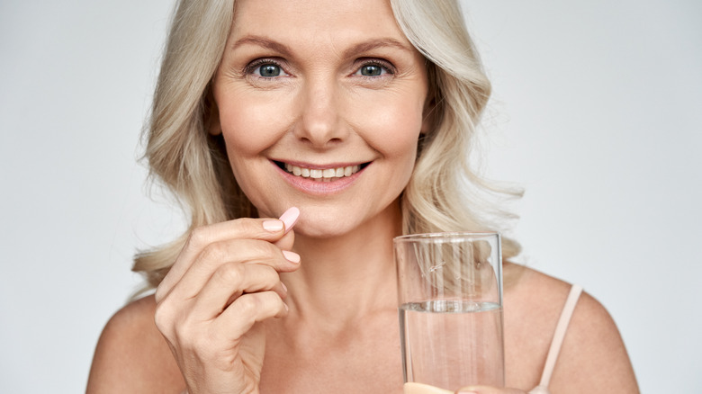 Woman smiles with a pill and water