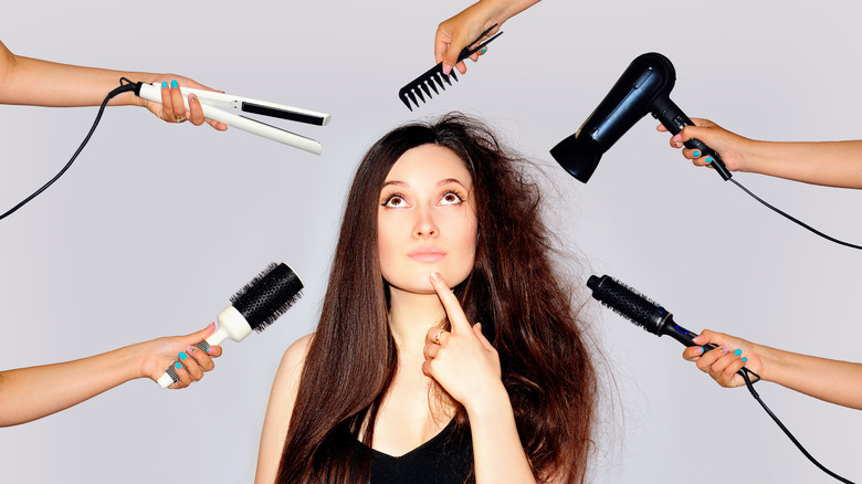 brunette woman surrounded by hair tools