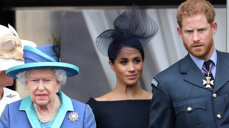 Prince Harry, Queen Elizabeth, and Meghan Markle posing 